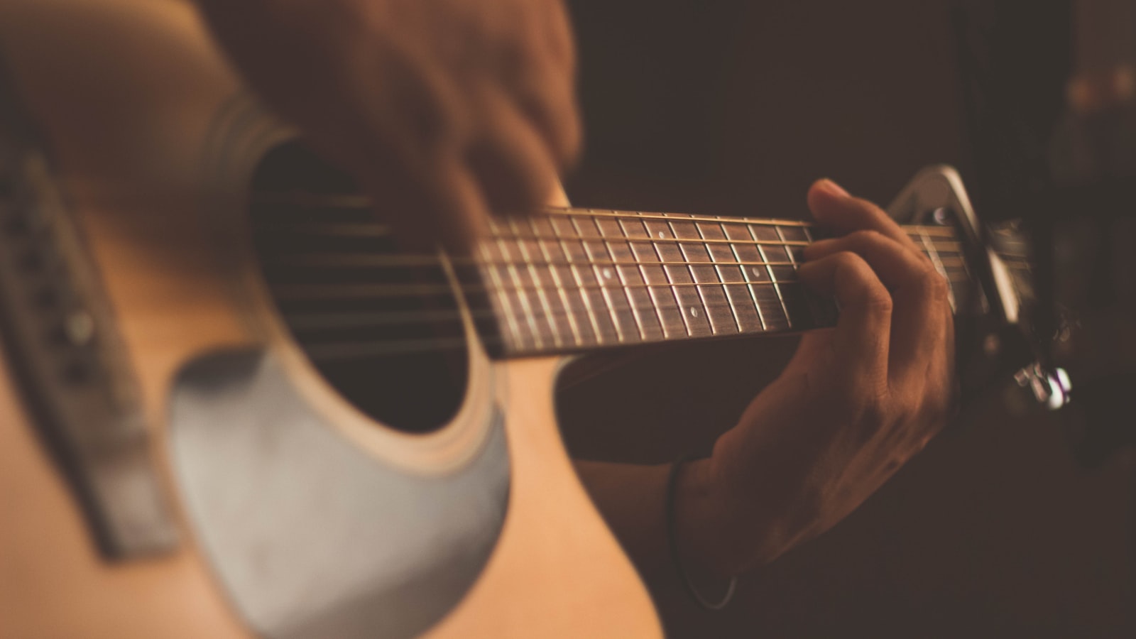 An affordable acoustic guitar resting against a wall at home.