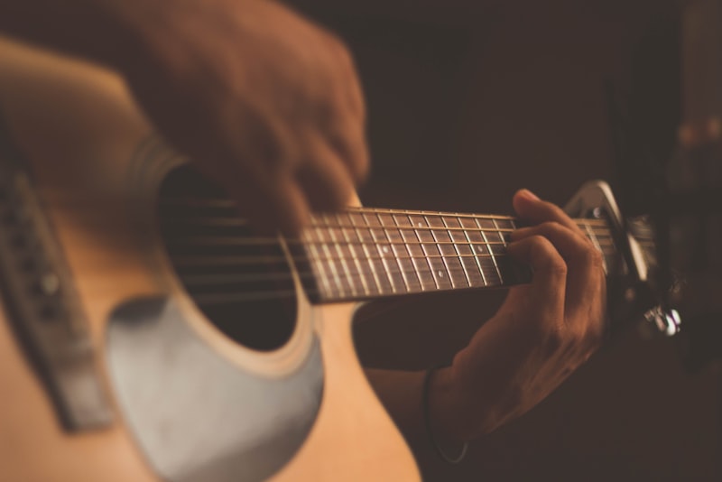 An affordable acoustic guitar resting against a wall at home.