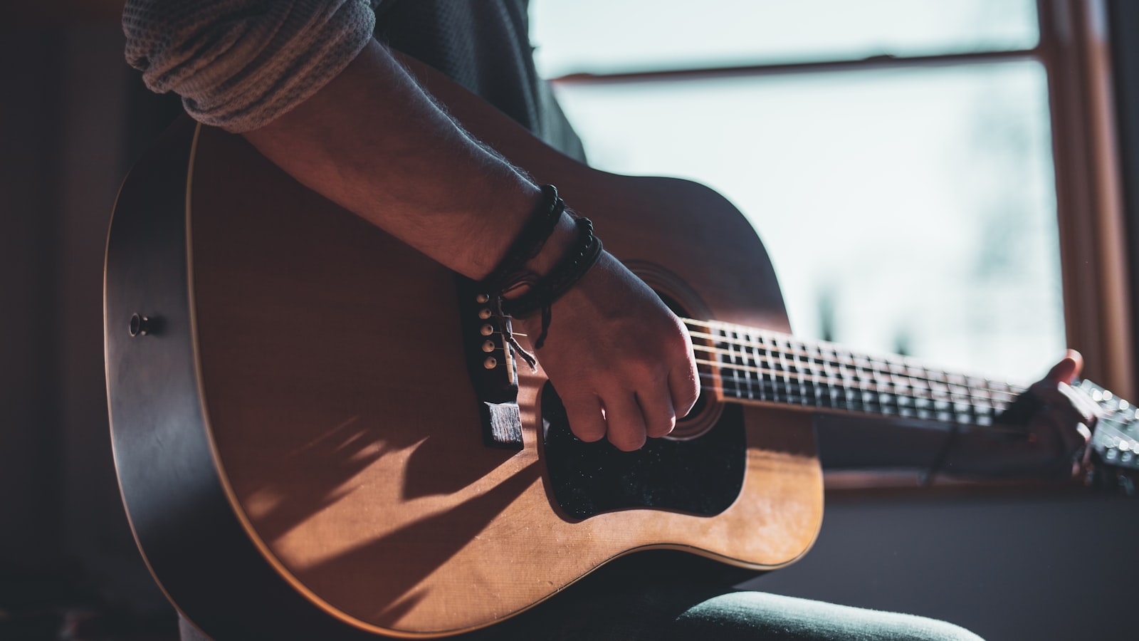 A guitarist's left hand fretting a chord high on the neck.