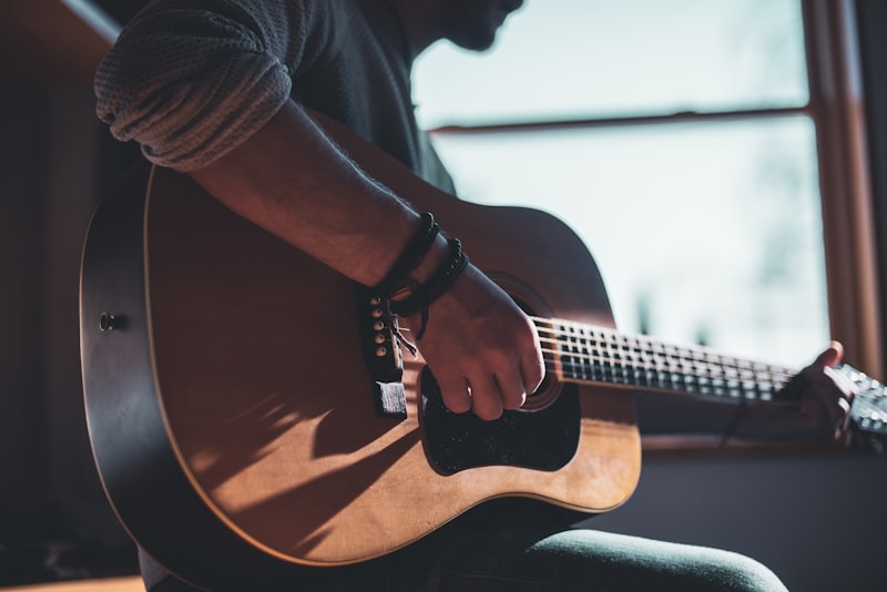 A guitarist's left hand fretting a chord high on the neck.